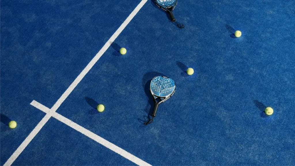 Two padel rackets and balls on a blue padel court