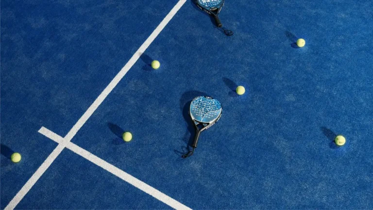 Two padel rackets and balls on a blue padel court